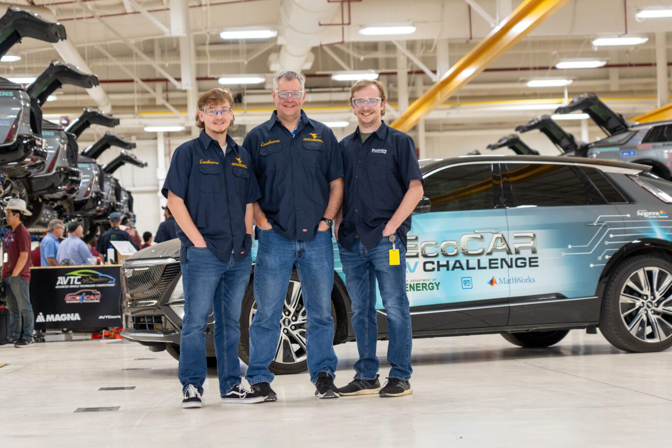 Image of three males with white skin posing in front of an EcoCAR-branded vehicle.